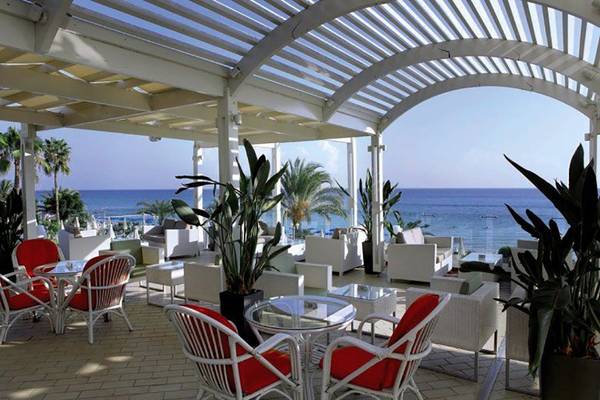 Terrasse des Sunrise Beach Hotels in Zypern mit Blick auf das Meer und weiße Möbel.