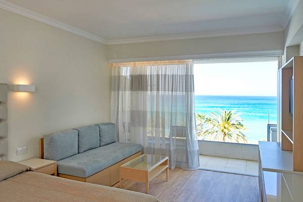 Zimmer mit Meerblick im Sunrise Beach Hotel in Zypern mit Bett, Sofa, Tisch und offenem Balkon.