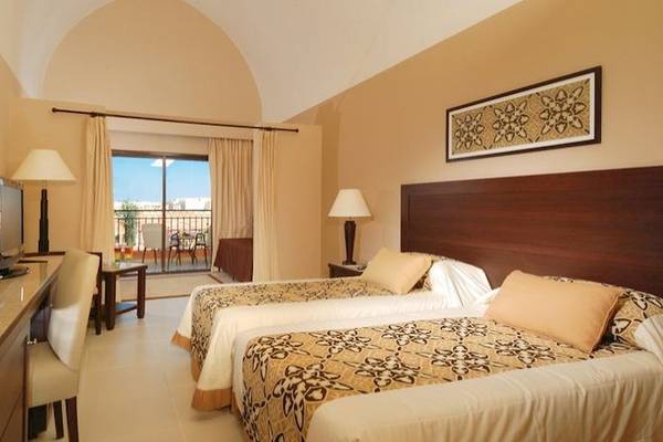 Hotelzimmer im JAZ Neo Dar El Madina mit zwei Betten, Fernseher, Schreibtisch und Balkon.