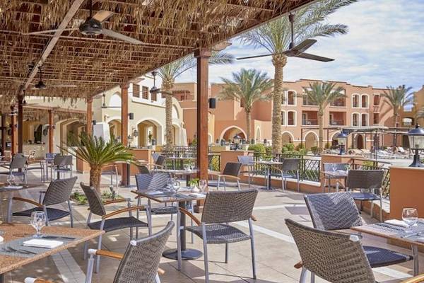 Restaurant-Terrasse im Jaz Neo Dar El Madina Hotel mit Tischen, Stühlen und Palmen im Hintergrund.
