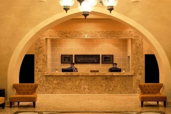 Reception im Jaz Neo Dar El Madina Hotel mit zwei Angestellten und modernen Möbeln.