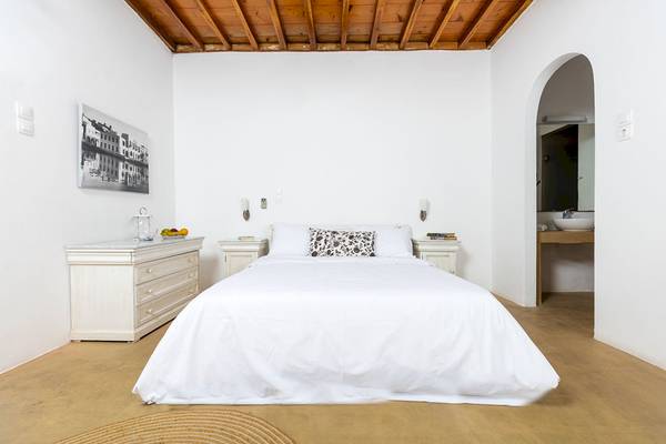 Schlafzimmer im Rhenia Mykonos Hotel & Bungalows mit weißem Bett und Möbeln.