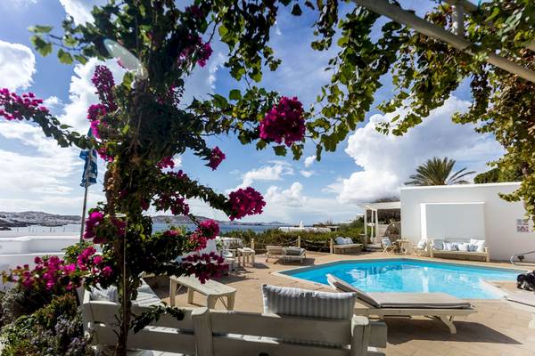 Außenpoolbereich des Rhenia Mykonos Hotel mit Blick auf das Meer und Loungemöbeln.