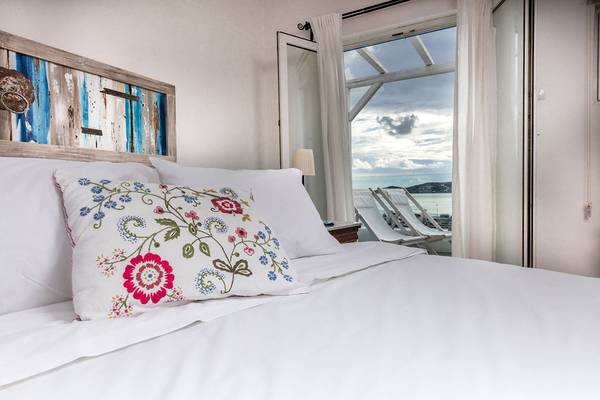 Schlafzimmer im Rhenia Mykonos Hotel mit Blick auf das Meer und weißen Möbeln.