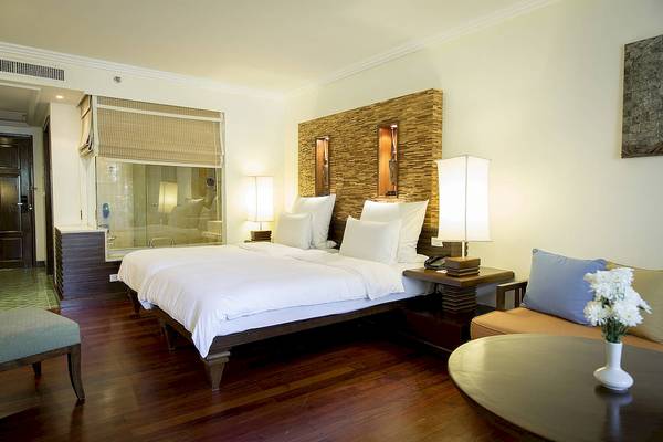 Schlafzimmer im Robinson Khao Lak Hotel mit zwei Betten, Kissen, Lampen und einer Couch.
