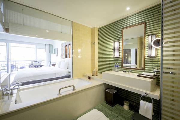 Badezimmer im Robinson Khao Lak Hotel mit Badewanne, Spiegel und grünen Wänden.