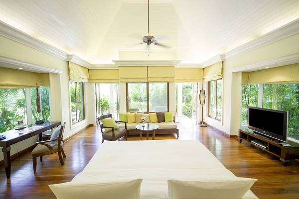 Schlafzimmer im Robinson Khao Lak Hotel mit großer Aussicht auf den Garten, modernes Design, große Fenster, bequemes Bett und Wohnbereich.