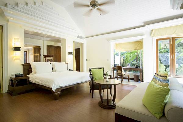 Schlafzimmer im Robinson Khao Lak Hotel mit großem Bett, grünen Kissen und Holzmöbeln.