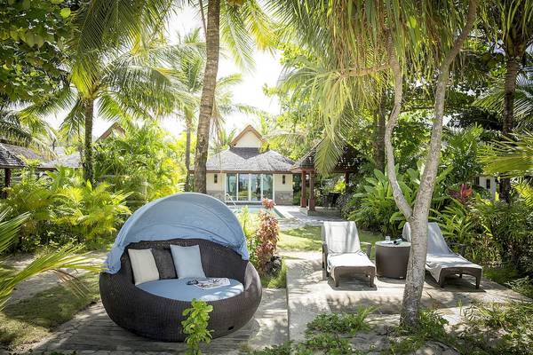 Lounge-Bereich des Robinson Khao Lak Hotels mit überdachtem Korbsofa und Sonnenliegen