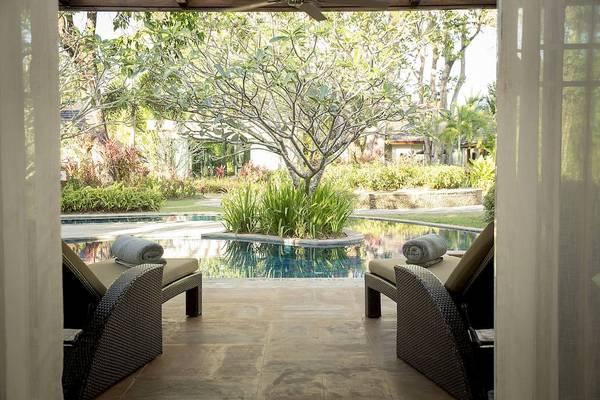 Blick von einem Zimmer des Robinson Khao Lak Hotels auf zwei Liegen am Pool.