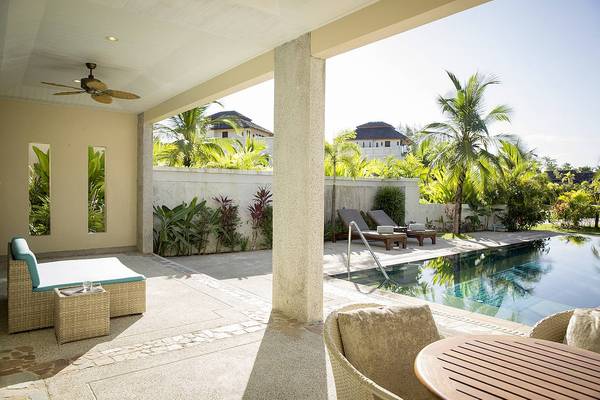 Terrasse mit Sonnenliegen und Pool im Robinson Khao Lak Hotel.