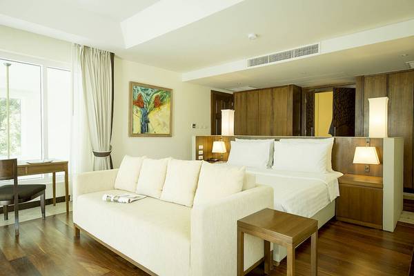 Das Schlafzimmer im Robinson Khao Lak Hotel mit einem großen Bett, einer Couch, und einem Schreibtisch.