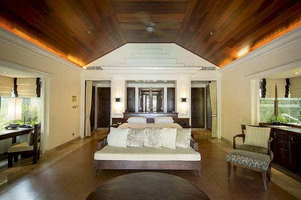 Luxuriöses Schlafzimmer im Robinson Khao Lak Hotel mit Doppelbett, Sofa, Schreibtisch und Holzboden.