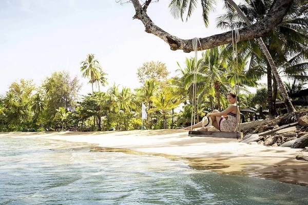 Frau sitzt auf einer Schaukel am Robinson Khao Lak Strand.