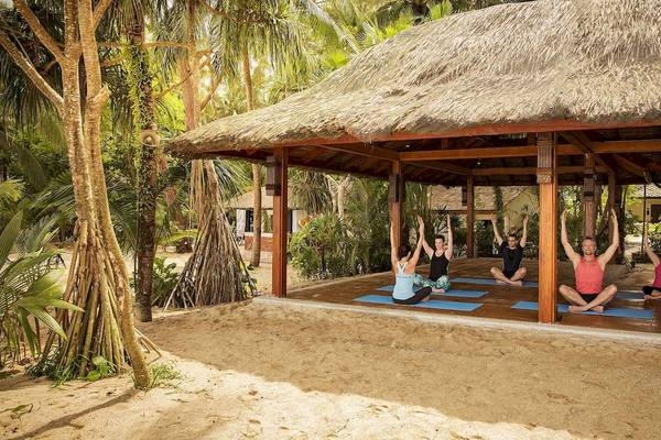 Gruppe von Frauen und Männern, die Yoga unter einem Dach in Robinson Khao Lak machen.