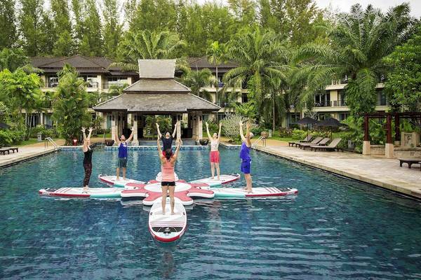 Gruppe von Menschen, die Yoga auf Surfbrettern im Pool des Robinson Khao Lak Hotels machen.
