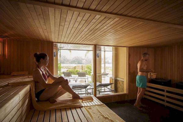 Eine Frau sitzt in der Sauna des Robinson Khao Lak Hotels, während ein Mann daneben steht.