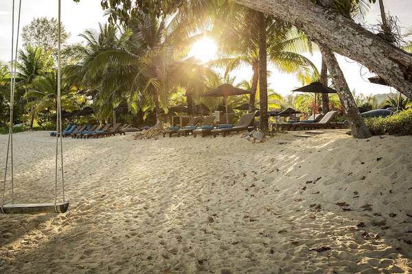 Strand des Robinson Khao Lak mit Schaukel und Sonnenliegen im Sonnenlicht.