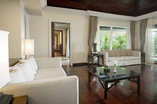 Wohnzimmer im Robinson Khao Lak Hotel mit weißen Möbeln, Holzboden und großen Fenstern.