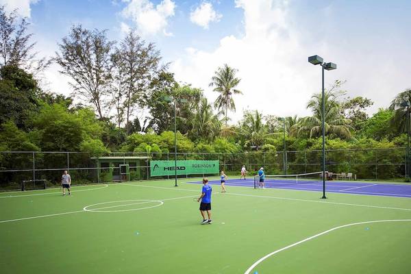 Tennisplatz im Robinson Khao Lak Hotel mit Spielern und Palmen im Hintergrund