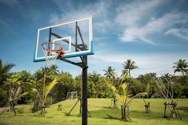 Basketballkorb im Freien unter einem blauen Himmel mit weißen Wolken.