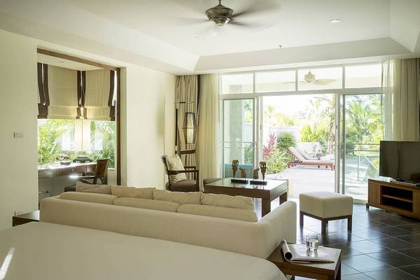Wohnzimmer des Robinson Khao Lak Hotels mit Möbeln, Fernseher und Terrassentür.