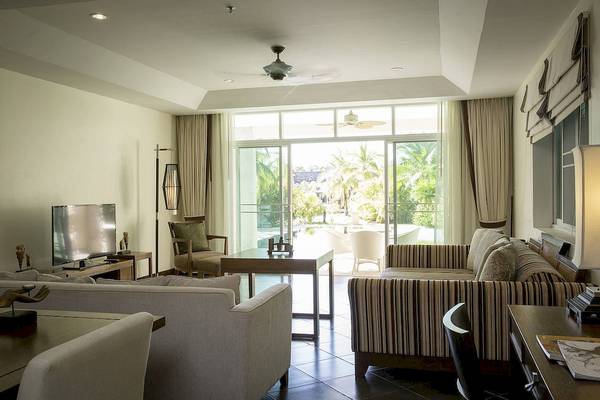 Wohnzimmer im Robinson Khao Lak Hotel mit großen Fenstern, Fernseher und Möbeln.