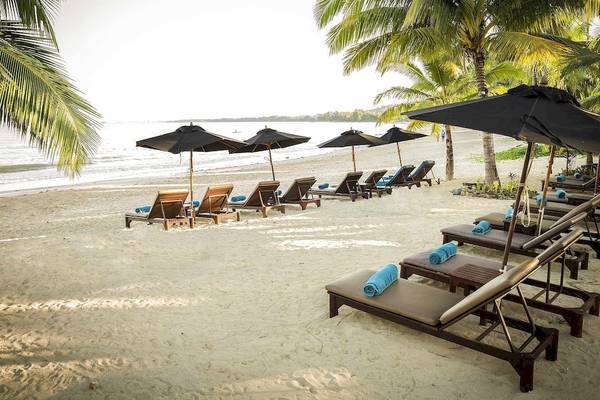 Strandszene im Robinson Khao Lak Hotel mit Lounge-Sesseln, Sonnenschirmen und Palmen
