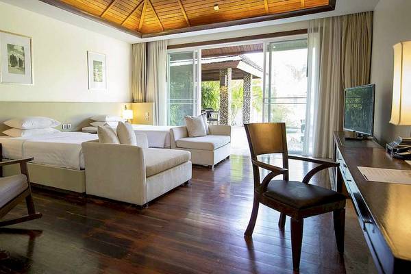 Suite-Zimmer im Robinson Khao Lak Hotel mit zwei Betten, Sofa, Schreibtisch und Fernseher.