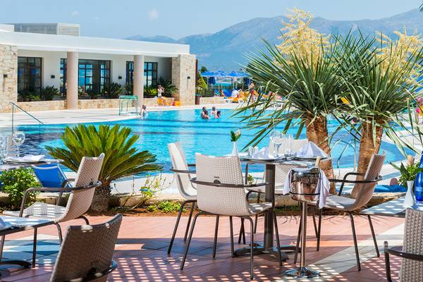 Außenterrasse des Grand Hotel Holiday Resort mit Tischen und Stühlen am Pool