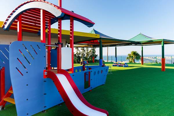Kinderspielplatz im Grand Hotel Holiday Resort mit Rutsche und schattenspendenden Dächern.