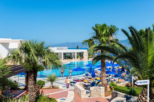 Außenbereich des Grand Hotel Holiday Resort mit Swimmingpool, Liegestühlen und Palmen