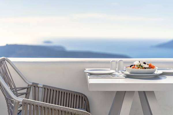 Ein Tisch auf einer Terrasse mit Blick auf das Meer, darauf steht ein Teller mit Salat.