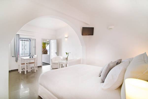 Schlafzimmer im Agali Houses mit Doppelbett, Sitzecke und Tisch, Fenster und Fernseher.