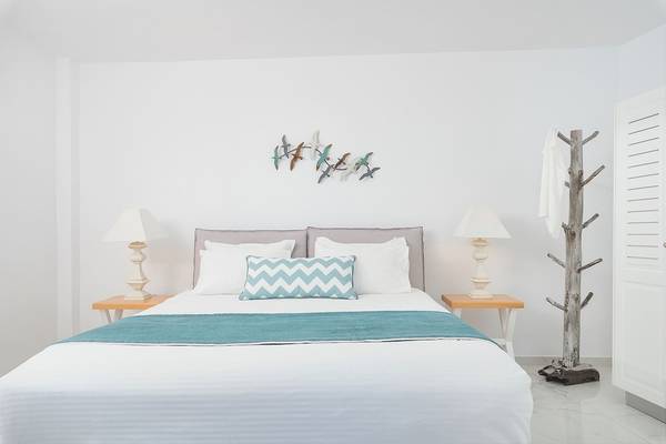 Schlafzimmer mit Bett, Lampen und Vogel Wandkunst in Agali Houses