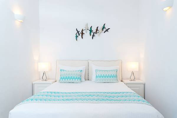 Schlafzimmer von Agali Houses mit weißen Wänden, einem Doppelbett und zwei Nachttischen mit Lampen.