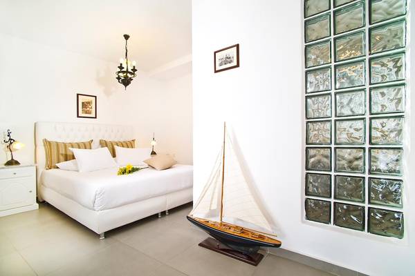 Schlafzimmer im Agali Houses Hotel mit einem großen Bett, Modellboot und modernen Wanddesigns.