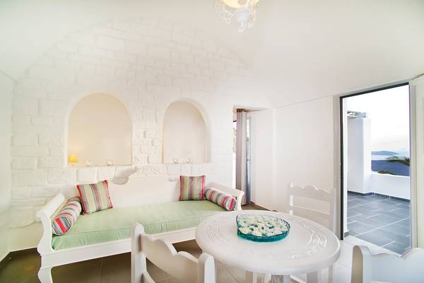 Innenansicht eines Zimmers im Hotel Agali Houses mit weißem Möbeln, grüner Bettdecke und Blick auf die Terrasse.