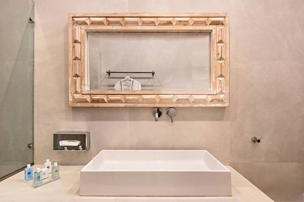 Badezimmer im Agali Houses Hotel mit zeitgenössischem Design, einem weißen Waschbecken und einem gerahmten Spiegel.