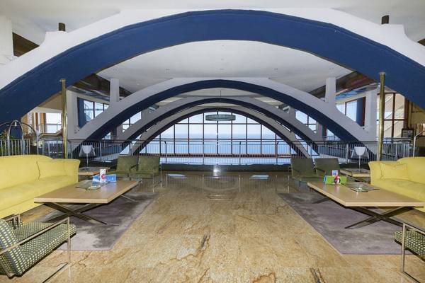 Hotellobby mit gelben Sofas und Meerblick durch große Glasfenster