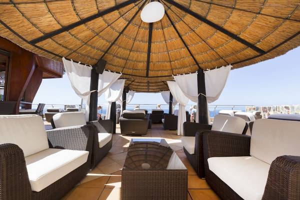 Loungebereich des Gloria Palace Amadores Thalasso & Hotel mit weißen Möbeln und einem großen Sonnenschirm.