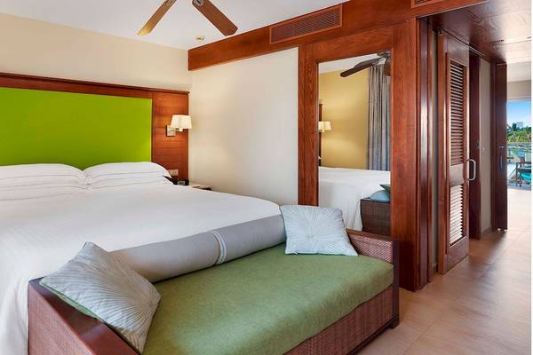 Schlafzimmer im Barcelo Bavaro Palace Hotel mit grüner Kopfseite, weißen Bettlaken und einer grünen Bank.