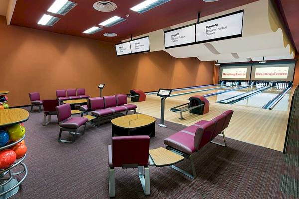 Innenansicht der Bowlinghalle im Barcelo Bavaro Palace Hotel mit Bowlingbahnen, roten Stühlen und Bowlingkugeln.