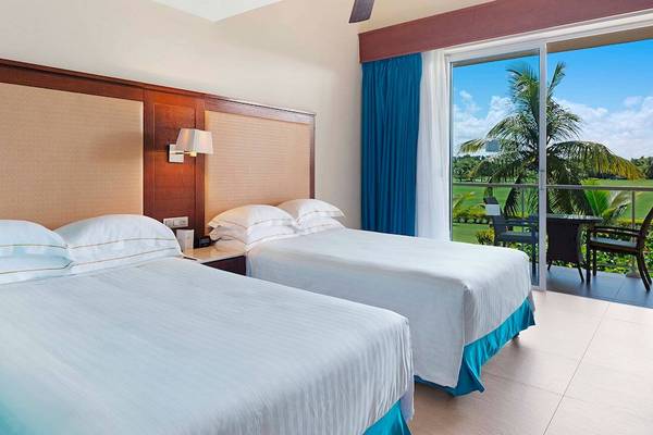 Zimmer im Barcelo Bavaro Palace mit Aussicht auf den Golfplatz und Terrasse mit Tisch und Stühlen.