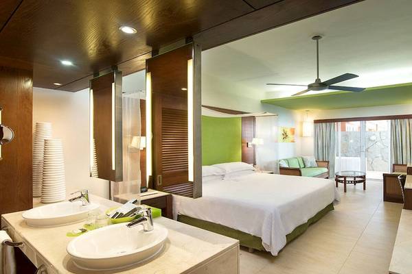 Schlafzimmer des Barcelo Bavaro Palace Hotels mit Doppelbett, Badezimmer und Fernseher.