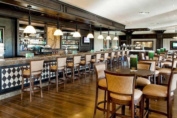Innenansicht der Bar des Barcelo Bavaro Palace Hotels mit Holzboden und Stühlen.