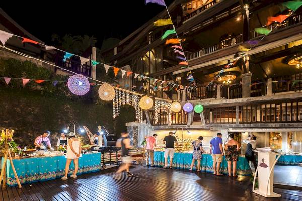 Abendbuffet im Nora Buri Resort & Spa mit bunten Fahnen und Gästen, die Speisen genießen.