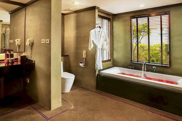 Badezimmer des Nora Buri Resort & Spa mit Badewanne, Toilette und Waschbecken.