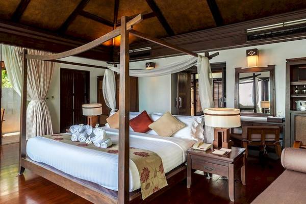 Schlafzimmer im Nora Buri Resort & Spa mit Himmelbett, Holzboden und moderner Einrichtung.