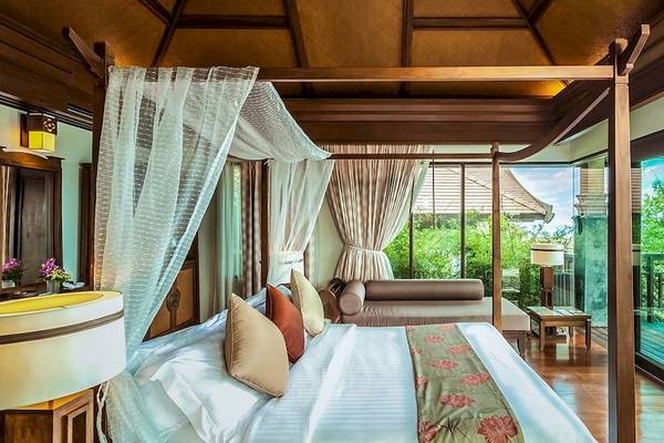 Luxuriöse Suite im Nora Buri Resort mit Poolblick, Baldachinbett, Wohnzimmerbereich und Terrasse.